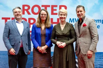 Bettina Martin und Manuela Schwesig stehen zwischen zwei Männern vor einem Plakat der Berlinale.