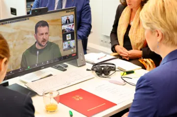 Manuela Schwesig am rechten Bildrand schaut auf einen Laptop, auf dem Selenskyj spricht. 